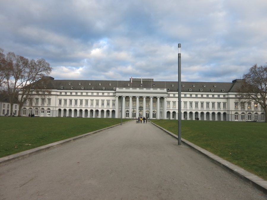 Château blanc avec portique à colonnes au bout d’une allée dans une pelouse.