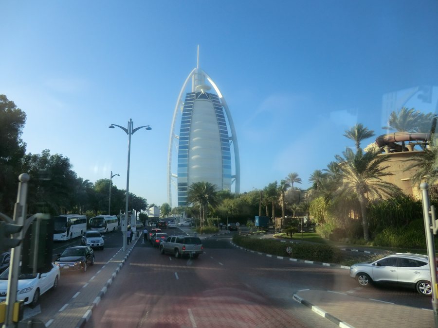 Le Burj Al Arab derrière une route animée et des palmiers à Dubaï